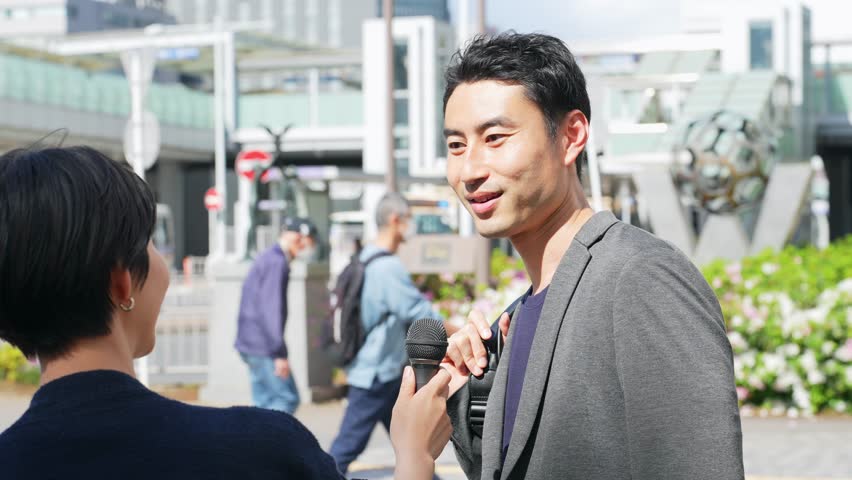 Asian man being interviewed on the street. TV broadcasting. Interviewee. Royalty-Free Stock Footage #1104558709