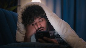 Sleepy tired Arabian guy exhausted napping Latino man boring Indian male at night home under blanket cover with duvet scrolling mobile phone addict smartphone reading social media sleeping fall asleep - Powered by Shutterstock - Get 15% off with code: PIKWIZARD15