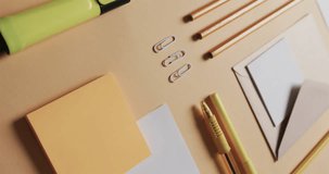 Vertical video of close up of pencils and stationery arranged on beige background, in slow motion. Desk, communication, workspace, stationery and order concept.