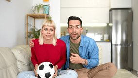 Young couple watching a football game on television from the comfort of their home.