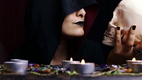 Witch hands holding and kissing a scary skull for a black magic ritual on a magical altar. Sorcerer rite of witchcraft and occultism. Halloween occult, esoteric and divination concept. - Powered by Shutterstock - Get 15% off with code: PIKWIZARD15