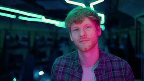 Laughing ginger man gamer walking at the camera after playing RPG video game on a championship. Stylish Neon Cyber Games