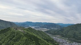 Ancient castle ruins on green mountain in Japanese landscape