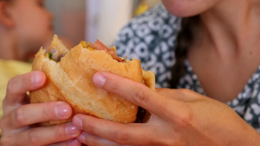 A woman and her children eat fast food hamburgers and fries at a restaurant | Shutterstock HD Video #1104570793