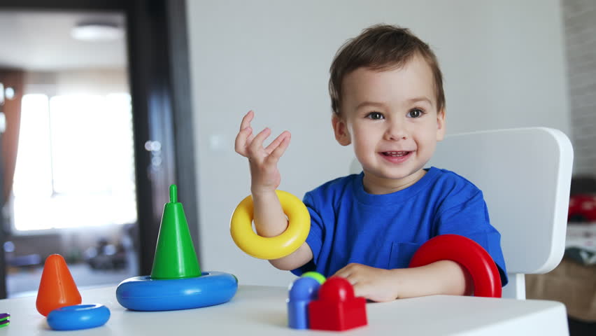 Adorable kid holding the rings from pyramid on his hands. Beautiful child smiling to the camera.