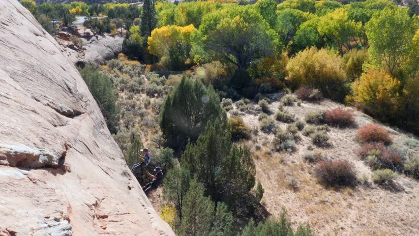 A father teaches his son how to rappel down a large desert cliff | Shutterstock HD Video #1104571793