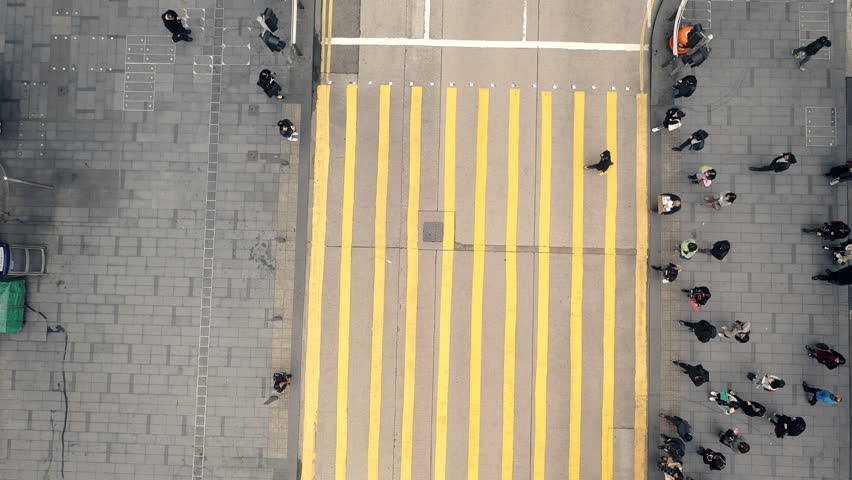 Aerial view, pedestrian crosswalk and city for street travel, society and urban population outdoors. Crowd, people and walking at zebra crossing, yellow lines or public road in busy town at rush hour Royalty-Free Stock Footage #1104571875