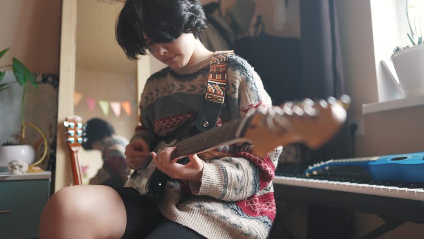 teenage girl plays electric guitar in her room. happy family music dreams concept. guitarist girl teenager. learning to play electric guitar at home. young female lifestyle musician playing guitar