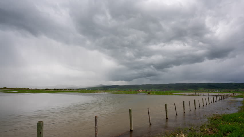 Timelapse of rainstorm moving over the landscape in Star Valley Wyoming as wind blows water in the flooded fields along the Salt River moving through Afton.