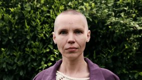 Bald woman portrait on a background of natural greenery. Freedom, victory, chemotherapy concept.