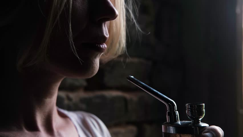 A woman smokes marijuana using a device. Cannabis use.