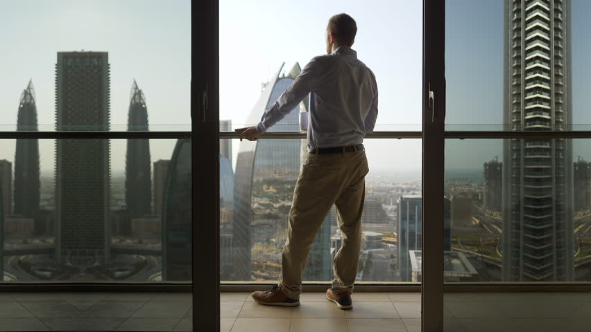 Young Succesful Business Person Standing on Balcony of High Rise Office City Building Overlooking Cityscape View - Entrepreneur Thinking About New Start-Up Business Ideas