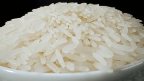 The camera zooms in to capture the mesmerizing sight of the rice grains falling. Each grain seems to dance in the air, as if weightless, before gently landing in the bowl. 4K
