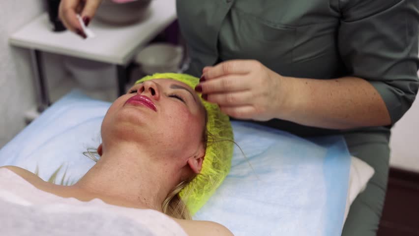 Wiping face, cotton pads, cosmetology clinic. Beautician cleaning face of patient, cosmetologist wiping face and neck of patient with cotton pads | Shutterstock HD Video #1104585439