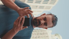VERTICAL VIDEO, Young man with beard uses map application on mobile phone