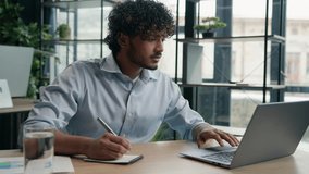 Indian Arabian man accountant writer business entrepreneur businessman write notes in notebook latino guy writing ideas report paperwork on office table studying online with laptop educational course - Powered by Shutterstock - Get 15% off with code: PIKWIZARD15