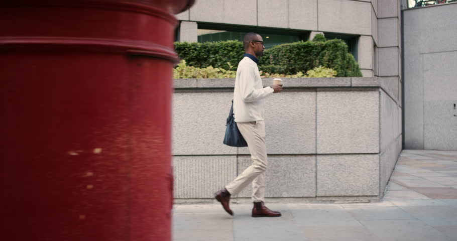 Coffee, walking and a black man in the city in the morning for a commute to work. Side, professional and an African employee on a walk on the sidewalk in a town for a job or career with a drink Royalty-Free Stock Footage #1104599003