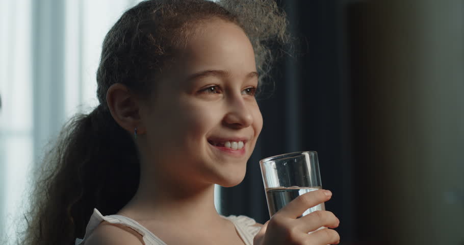 Little girl drinks water. Close up Kid drinking cup water healthy dody care. Healthy lifestyle Children. Cute Child Girl Drinking Glass Fresh Transparent Pure Filtered Mineral Water at Home.