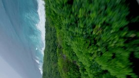 Vertical video. Mountain speed dive jungle vegetation sea ocean wave paradise beach tropical nature landscape aerial view. FPV sport drone shot exotic seashore coastline lagoon island bay coast stone