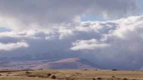 Clouds over the snow mountains time lapse, top view, big cloudscape fast building in horizon, beautiful panoramic view in autumn time. Filmed in cinema camera, 8K downscale, 4K.