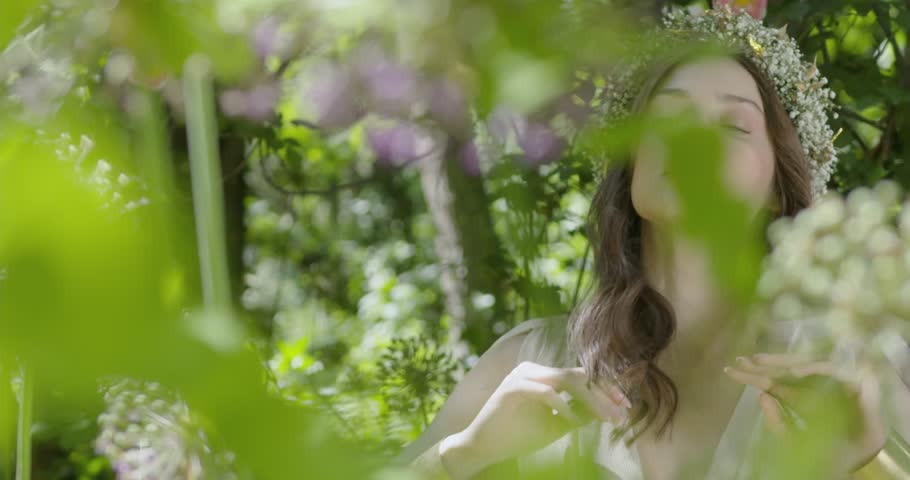 Woman with wreath of flowers stands in the garden