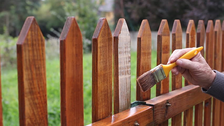 Painting protective varnish on wooden picket fence at backyard. Motion of hand with paintbrush. Handheld shot Royalty-Free Stock Footage #1104613875