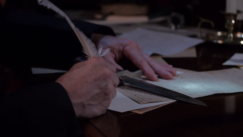 VIRGINIA - SPRING 2023 - Reenactment, Tabletop, quill writing, dipping ink and writing by candle light  by window in a church setting.  Hands of a man with Priest cassock writing at table with quill. Royalty-Free Stock Footage #1104620191