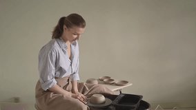 a woman in an apron in a pottery workshop works on a potter's wheel. slow motion video. woman potter. High quality Full HD video recording