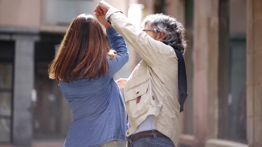 Smiling mature love couple cheerful retirees dancing holding hands on city street. Caucasian senior pensioners enjoying sightseeing vacation in Europe. Happy adult partner weekend romantic fun trip.  Royalty-Free Stock Footage #1104620875