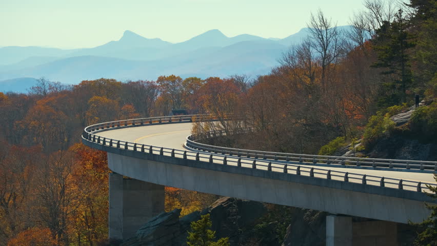 Mountain fall landscape with Linn Cove Viaduct, near Blowing Rock, Blue Ridge Parkway, North Carolina, USA. Driving cars on scenic road between autumnal woods Royalty-Free Stock Footage #1104620993