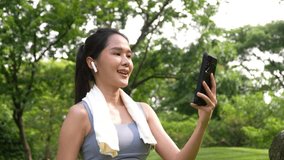 Asian woman attractive use smartphone for video conference with her friend after workout. Smiling sporty young woman working out outdoors and looking at camera. Healthy lifestyle well being wellness