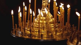 A golden large candlestick with burning candles on a dark blurred background of an Orthodox church. The theme of religious faith and God and traditions of Orthodox. Candles in an Orthodox church.