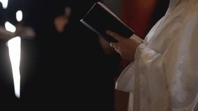 An Orthodox priest holds a Bible in his hands. Close-up of unrecognizable hands of a priest holding a bible in a church. A priest with a Bible. Christianity or Catholicism, faith in God. Church ritual