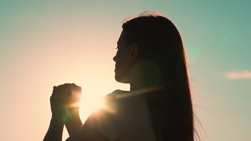 Relaxation and meditation in nature. Christian woman praying at sunset close-up. Girl on background of sky in rays of sun prayer to family and children. Faith in god. Apologize. Hope. Silhouette Royalty-Free Stock Footage #1104632143