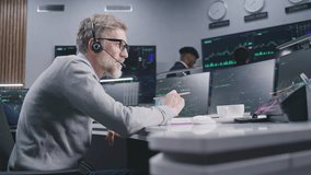 Male financial analyst in headset works in bank on multi-monitor computer with real-time stocks, writes data. Team analyze exchange crypto market charts on big digital screens. Trading and analytics. - Powered by Shutterstock - Get 15% off with code: PIKWIZARD15