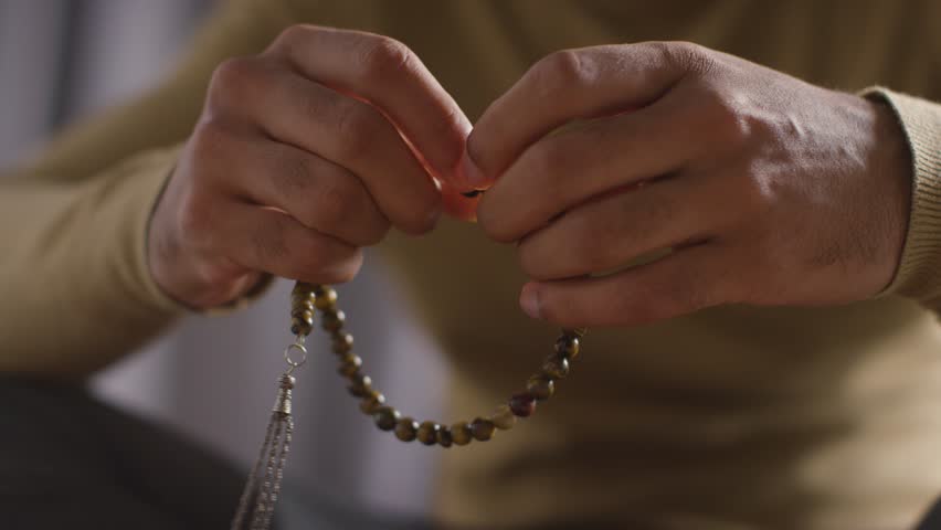 close up of muslim man praying holding prayer beads sitting on floor at home. Royalty-Free Stock Footage #1104639799
