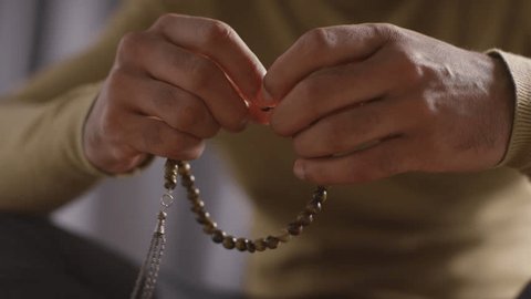close up of muslim man praying holding prayer beads sitting on floor at home. Video stock