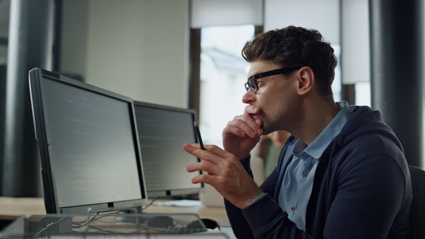 Focused programmer checking code at desk. It guy professional solving problem typing computer in office. Confident millennial man engineer looking screen creating software. Cyber security specialist Royalty-Free Stock Footage #1104643587