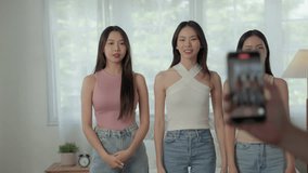 Group of young adult Asian females are influencers, content creators use smartphones record lively and dynamic dance videos in bedroom, creating captivating content to share on various social media