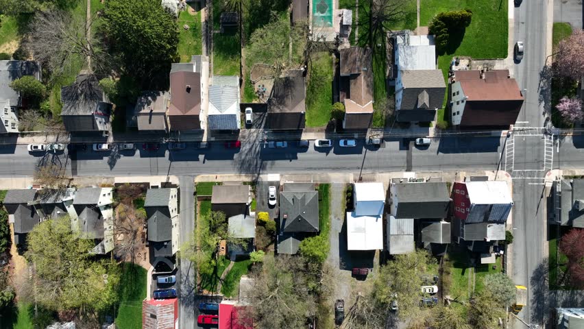 Top down aerial of houses in small town in spring. Drone truck shot above town street.