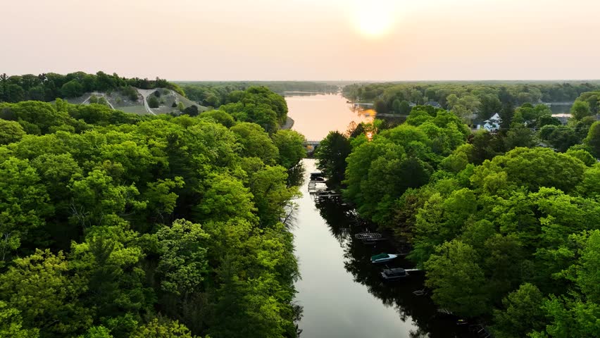 The sun rising in the distance from over a small channel connecting Lake Michigan to Mona Lake.