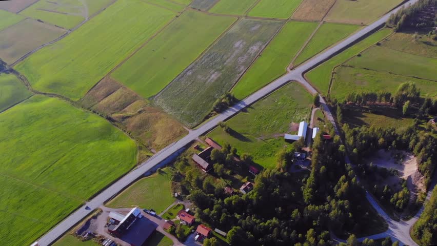 Drone shot from height facing down filming national road and field, in Sweden.