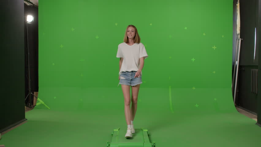 Woman in white t-shirt, jeans shorts and sneakers walking on a Green Screen, Chroma Key. 4k UHD front view footage video Royalty-Free Stock Footage #1104658745