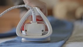 home electric iron, close-up. girl ironing clothes with an iron, close-up. tool for smoothing textiles and wrinkled clothes. the hostess is ironing clothes with a household electric iron. Slow motion.