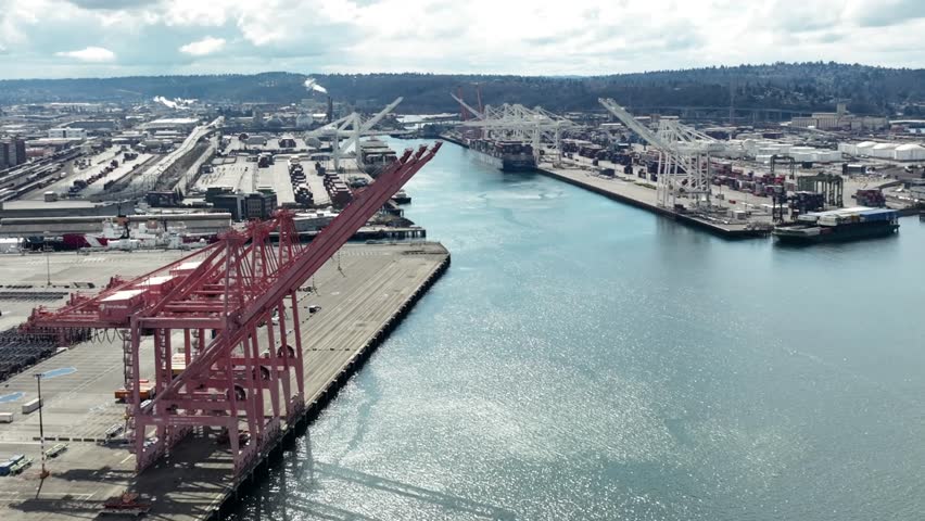 Aerial view across large red loading shipping cranes on Seattle harbor island terminal