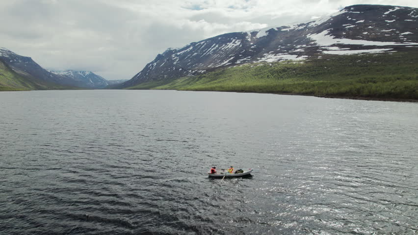 Aerial Fix Drone Shot of a Young Couple Crossing a Lake by Rowing a Boat in the Swedish Mountains, Kungsleden Trail, Teusajaure Mountain Cabin