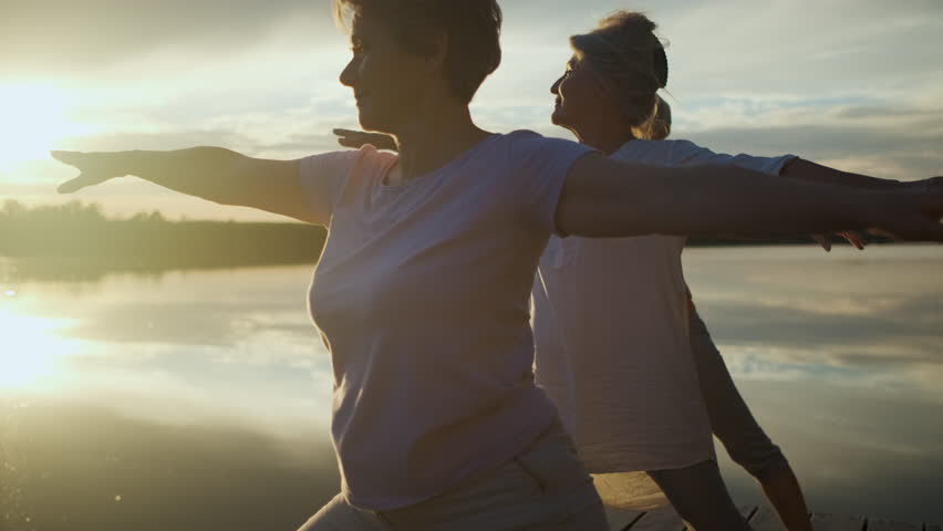 Group of senior woman doing yoga exercises by the lake. Royalty-Free Stock Footage #1104664569