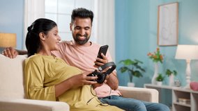 Happy indian husband placing headphones on belly for baby on pregnant wifes belly at home - concept of maternity, - Powered by Shutterstock - Get 15% off with code: PIKWIZARD15