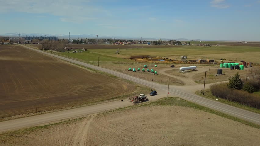 Aerial Panning Shot Of Farmers In Trailer Of Tractor At Countryside Against Sky On Sunny Day - Billings, Montana