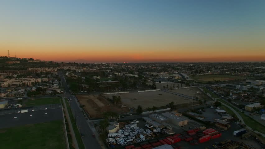 Aerial Panning Shot Of Suburb In City Against Orange Sky During Dusk, Drone Flying Over Neighborhood - Long Beach, California